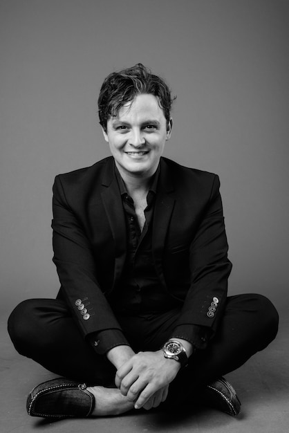 Portrait of Italian businessman wearing black suit on gray in black and white