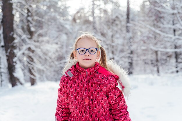 Portrait of ittle girl in eyeglasses in beautiful winter forest