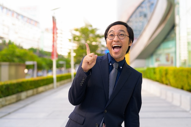 屋外の街で自然と新鮮な空気を取得する日本のビジネスマンの肖像画