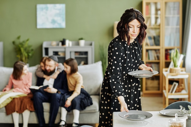은제품 복사 공간이 있는 젊은 여성이 식탁을 차리는 데 초점을 맞춘 집에 있는 유태인 가족의 초상화