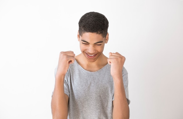 Portrait of a joyful African-American young man. Winning emotion of a black boy on a white background. 