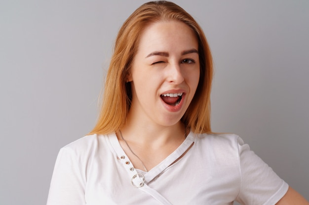 Portrait of joyful blonde young cute woman laughing over a gray 