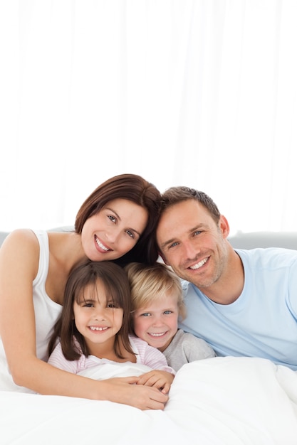 Portrait of a joyful family sitting on the bed