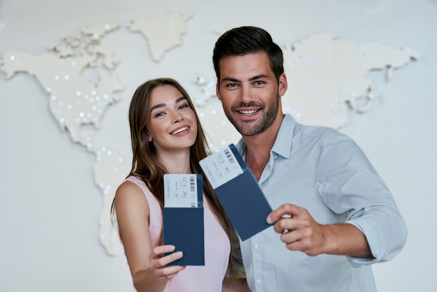 Photo portrait of joyful glad couple holding passport with flying tickets in hands