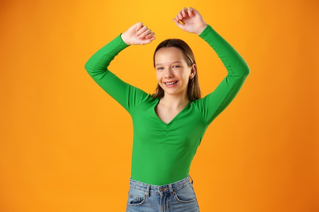 Портрет радостной счастливой девочки-подростка, празднующей успех на желтом фоне