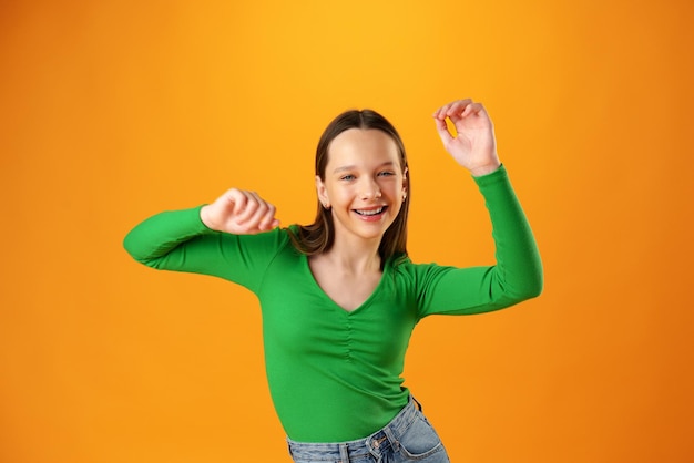 노란색 배경에서 성공을 축하하는 즐겁고 행복한 10대 소녀의 초상화