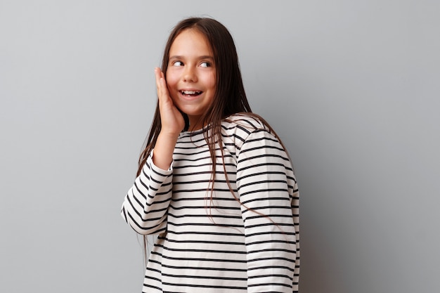 Portrait of joyful little girl laughing over a gray background