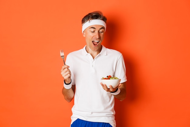 Portrait of joyful middle aged guy in workout uniform