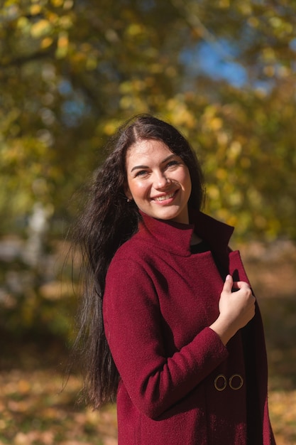 Portrait of a joyful young woman enjoying in the autumn park.