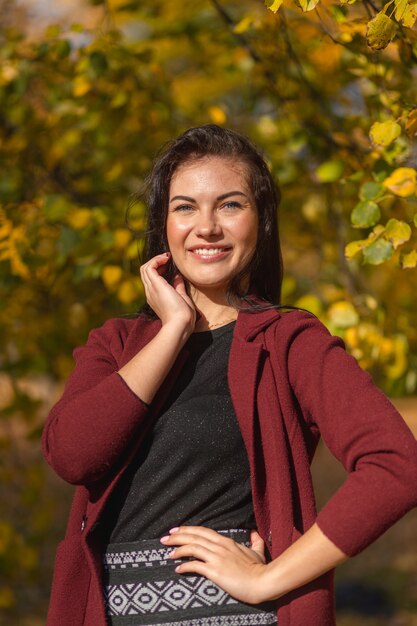 Портрет радостной молодой женщины, наслаждающейся в осеннем парке.