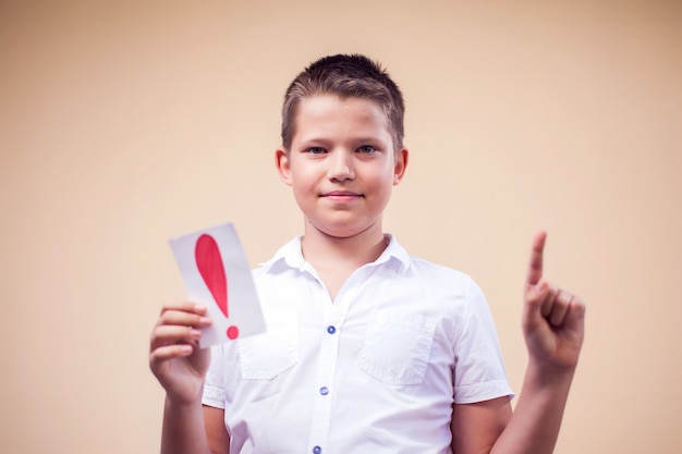 Ritratto di ragazzo ragazzo in possesso di carte con punto esclamativo. concetto di educazione e bambini