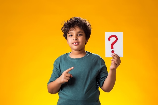 Portrait of kid boy holding question mark card in hand Education and curiosity concept