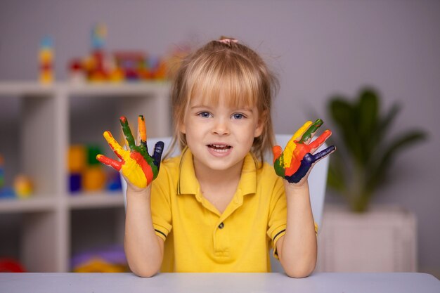 Portrait of kid girl with face and hands painted at home