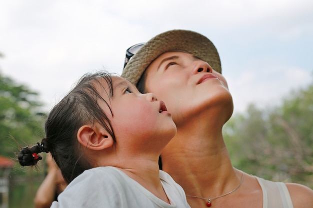 Ritratto della ragazza del bambino con la giovane madre che osserva in su.