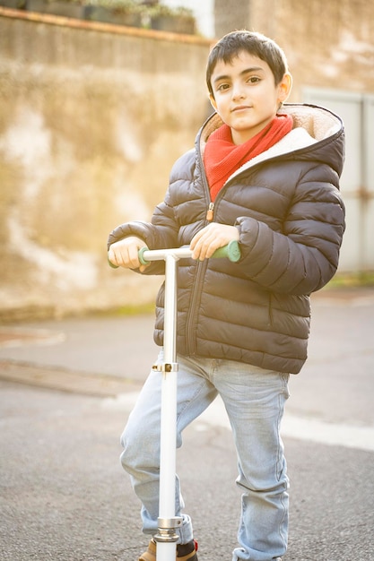 Foto ritratto di bambino con il suo scooter a spinta