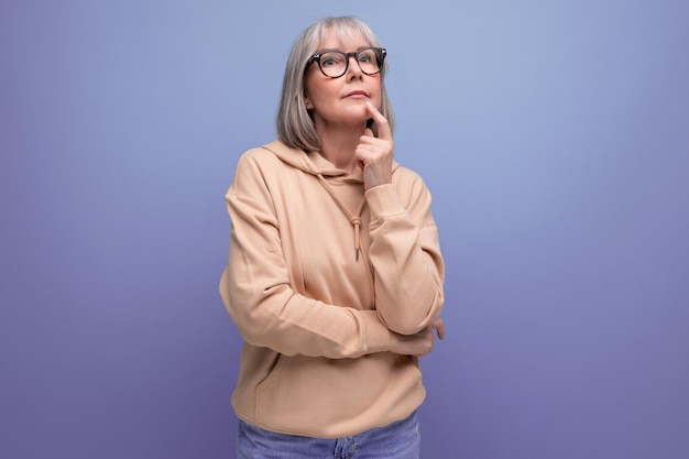 Portrait of a kind middleaged woman grandmother with gray hair in a casual youth look on a studio