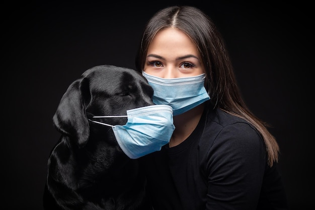Portrait of a Labrador Retriever dog in a protective medical mask with a female owner