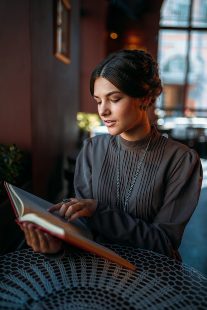 Portrait of lady in cafe reading book near window