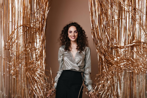 Portrait of lady in silver blouse posing on gold background