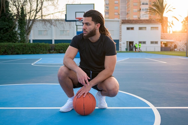 Portrait of a Latin Afro man posing with a ball on a basketball court