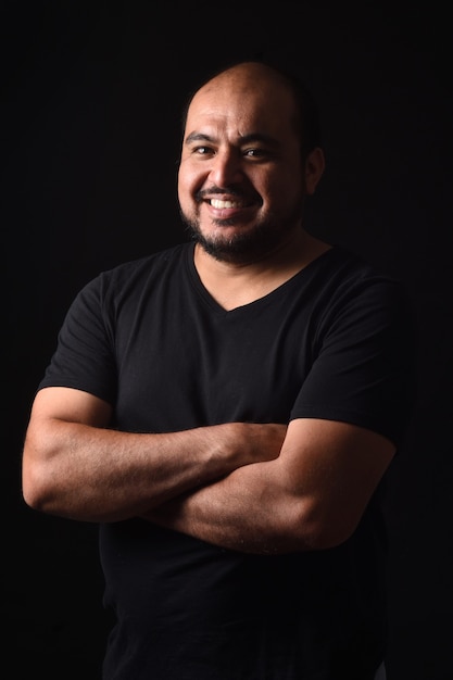 Portrait  of a latin american man arms crossed on black background