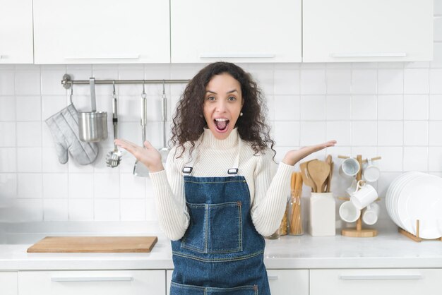 Portrait of a Latin woman smiling happily and showing various gestures in the kitchen.