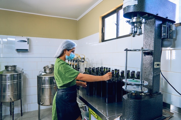 Portrait latin woman working in her small olive oil factory packaging and labeling