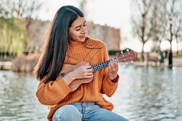 Foto ritratto di donna latina che gioca ukulele bruna donna ispanica con i capelli lunghi