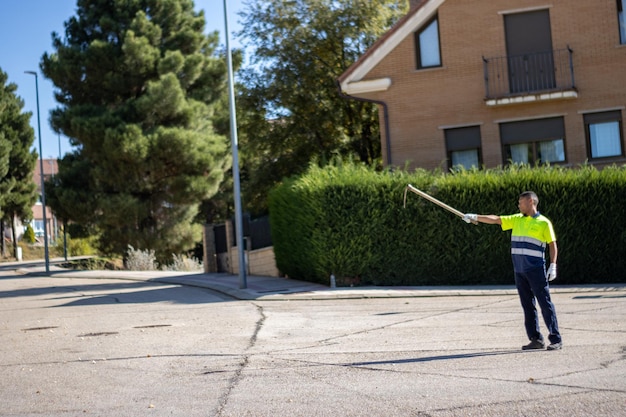 Portrait of a Latino municipal gardener worker pointing a hoe in the street