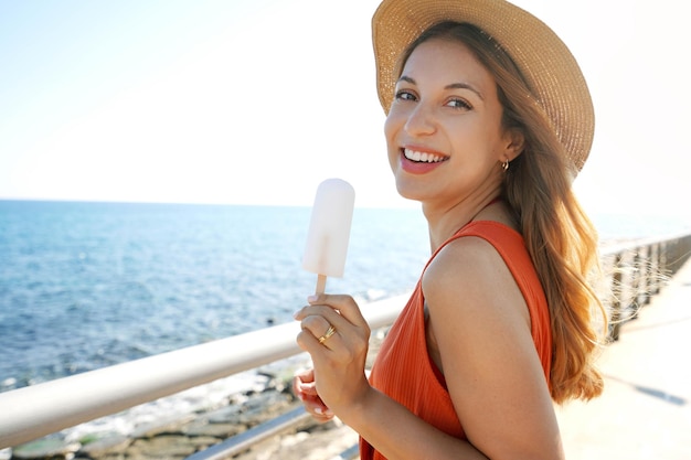 Photo portrait of laughing brazilian woman eating a lemon popsicle looking at the camera on summer