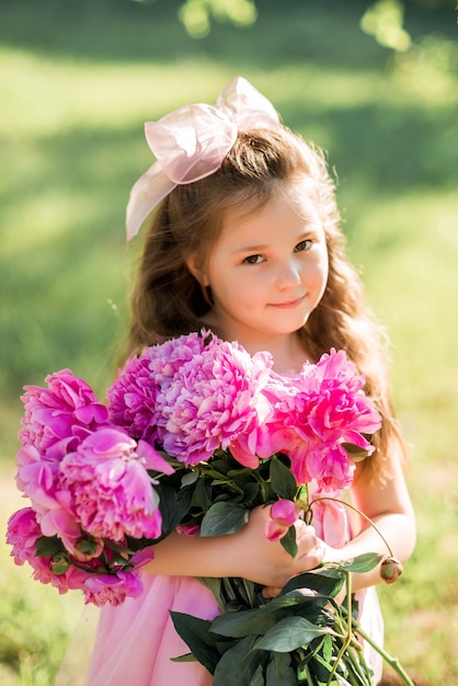 Portrait of a laughing girl with a bouquet of peonies.