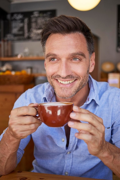 Portrait of laughing man with cup of coffee in a coffee shop