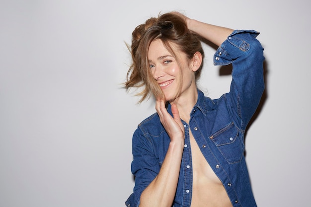 Portrait of laughing woman wearing fully unbuttoned denim shirt