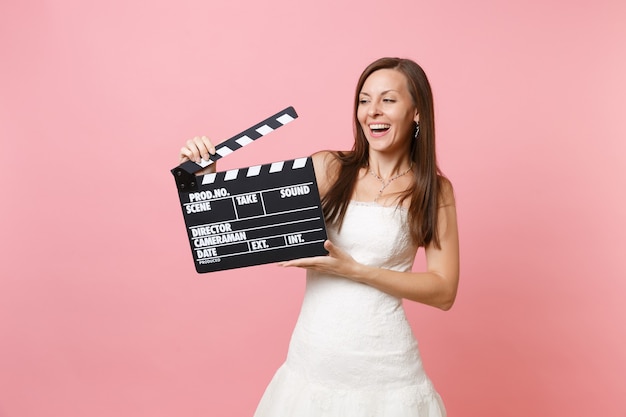 Portrait of laughing woman in white dress holding classic black film making clapperboard