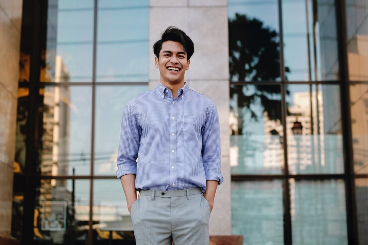Photo portrait of laughing young asian businessman in the city. looking at camera. a happy friendly man