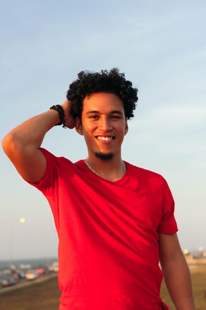 Portrait of laughing young man with curly hair standing in open air