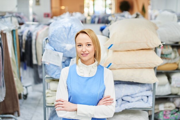 Portrait of a laundry worker on the background of clothes on hangers in dry cleaning