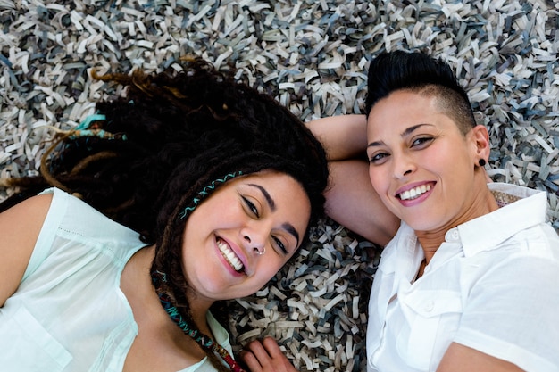 Portrait of lesbian couple lying on rug in living room