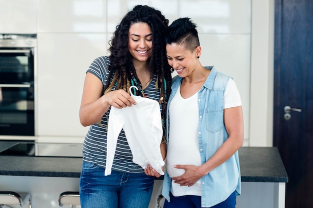 Portrait of lesbian couple standing together and looking at babys clothes