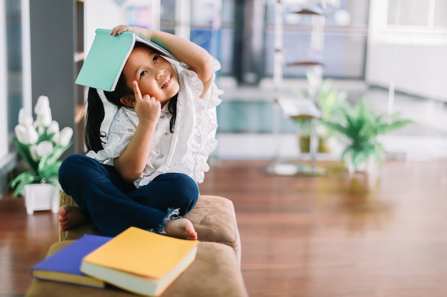 Portrait of little Asian child thinking and a book on the head.