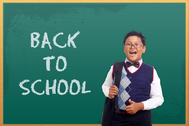 Portrait of little asian elementary school pupil with text of\
back to school on the board