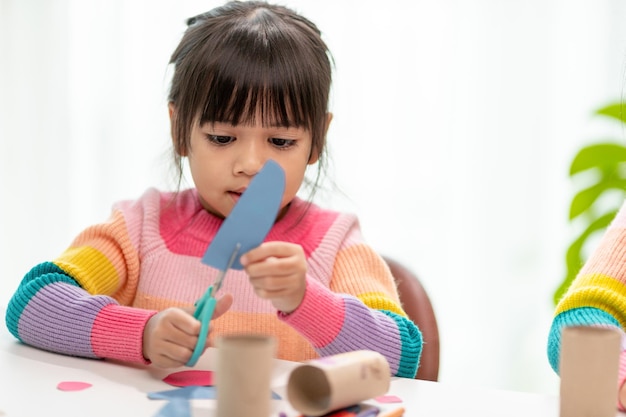 Portrait of a little asian girl cutting a paper in activities on DIY class at SchoolScissors cut paper