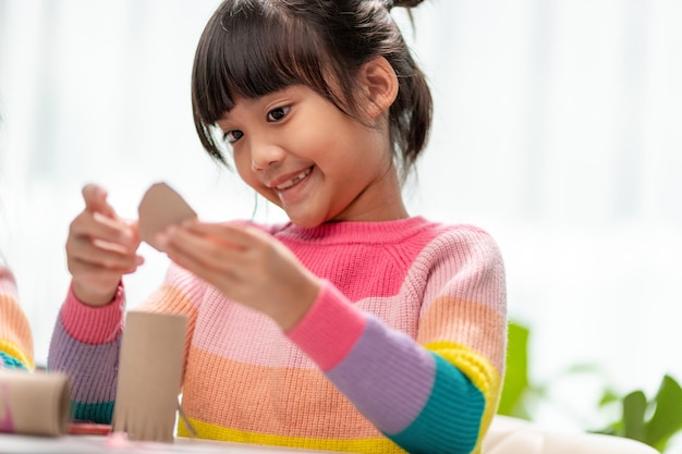 Портрет маленькой азиатской девочки, разрезающей бумагу на уроке DIY в SchoolScissors, разрезающей бумагу