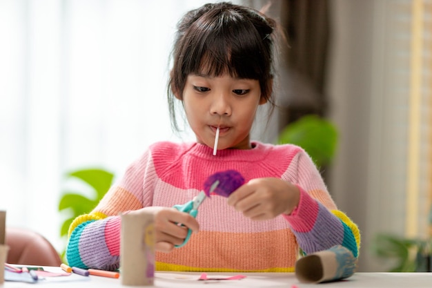 Portrait of a little asian girl cutting a paper in activities on DIY class at SchoolScissors cut paper