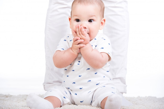 Portrait of a little baby boy is sitting on the floor.