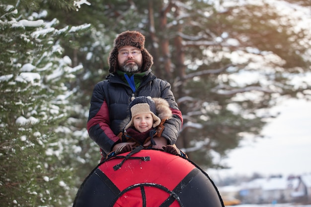 Piccolo bambino del ritratto e suo padre con il tubo nel giorno di inverno. divertimento all'aria aperta per le vacanze di natale in famiglia.