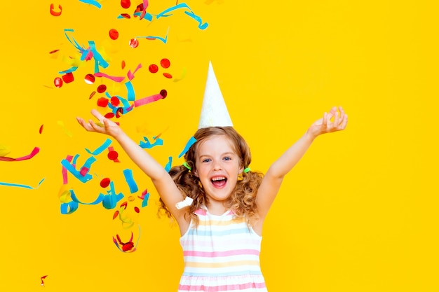 Portrait of a little beautiful girl celebrating her birthday. 
 colorful confetti. 