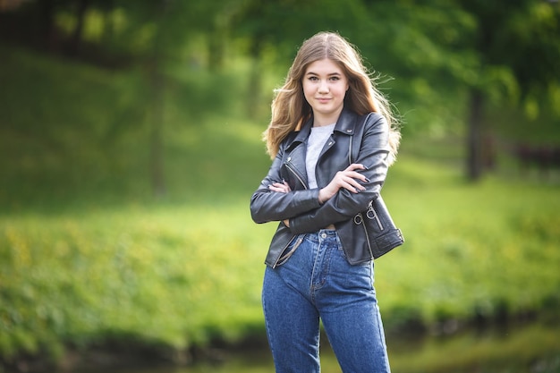 Portrait of little beautiful stylish kid girl in city park on green forest background