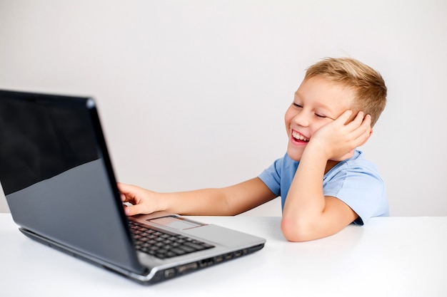 Portrait of little blond boy looking at laptop with wide eyes