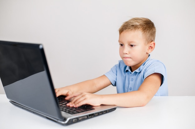 portrait of little blond boy looking at laptop with wide eyes